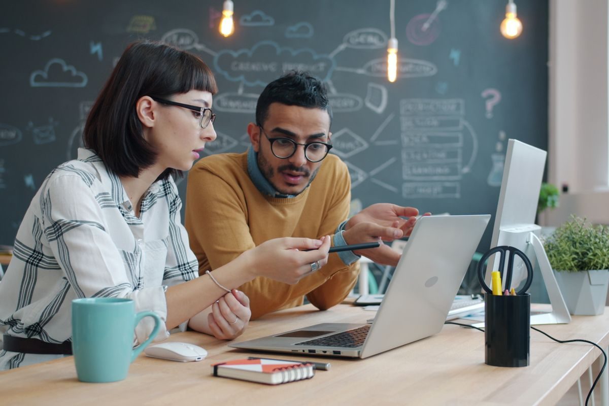 Two people talking through work at a desk